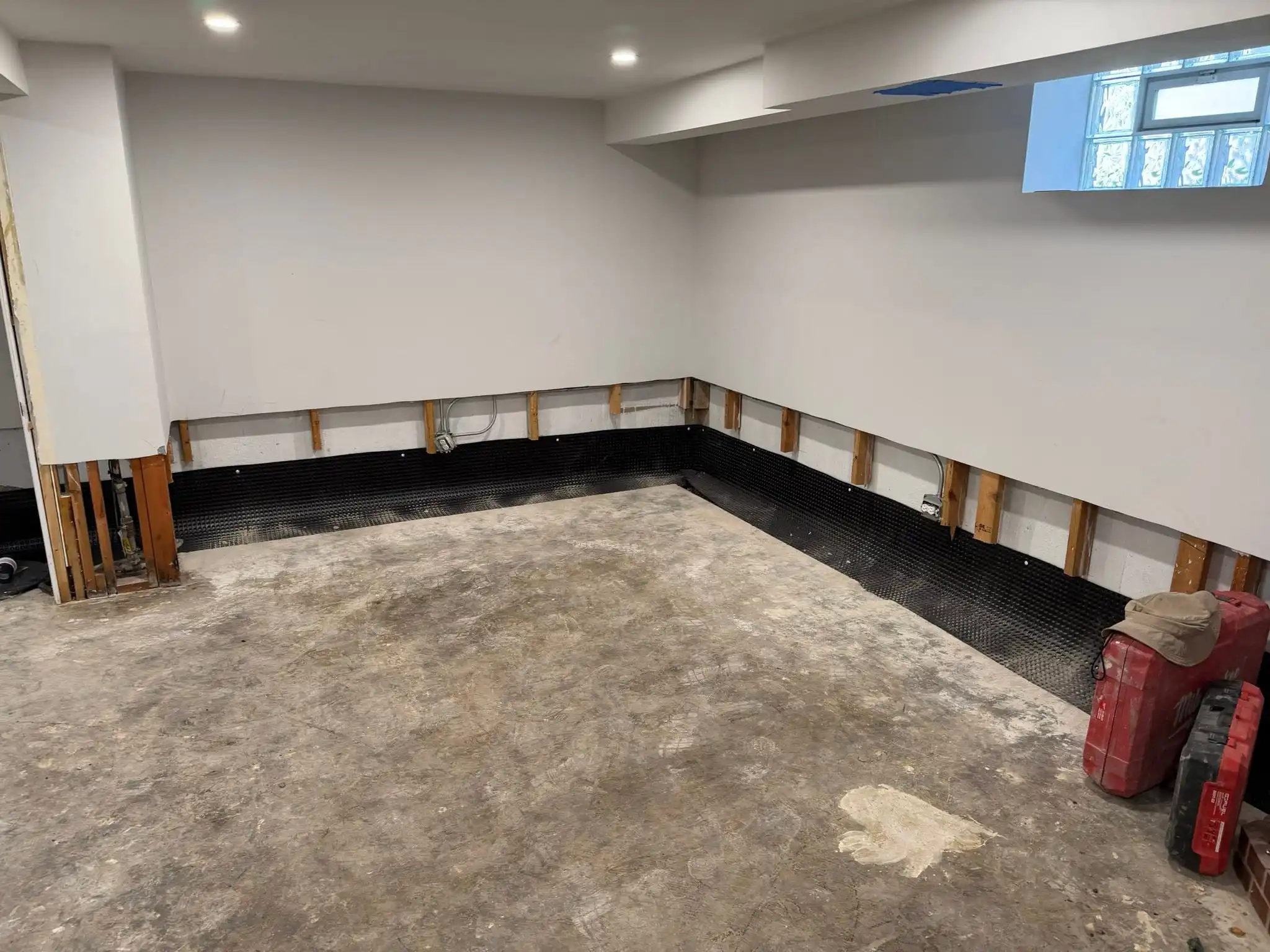 Interior basement perimeter with drainage membrane installed along the base of the foundation wall, Toronto