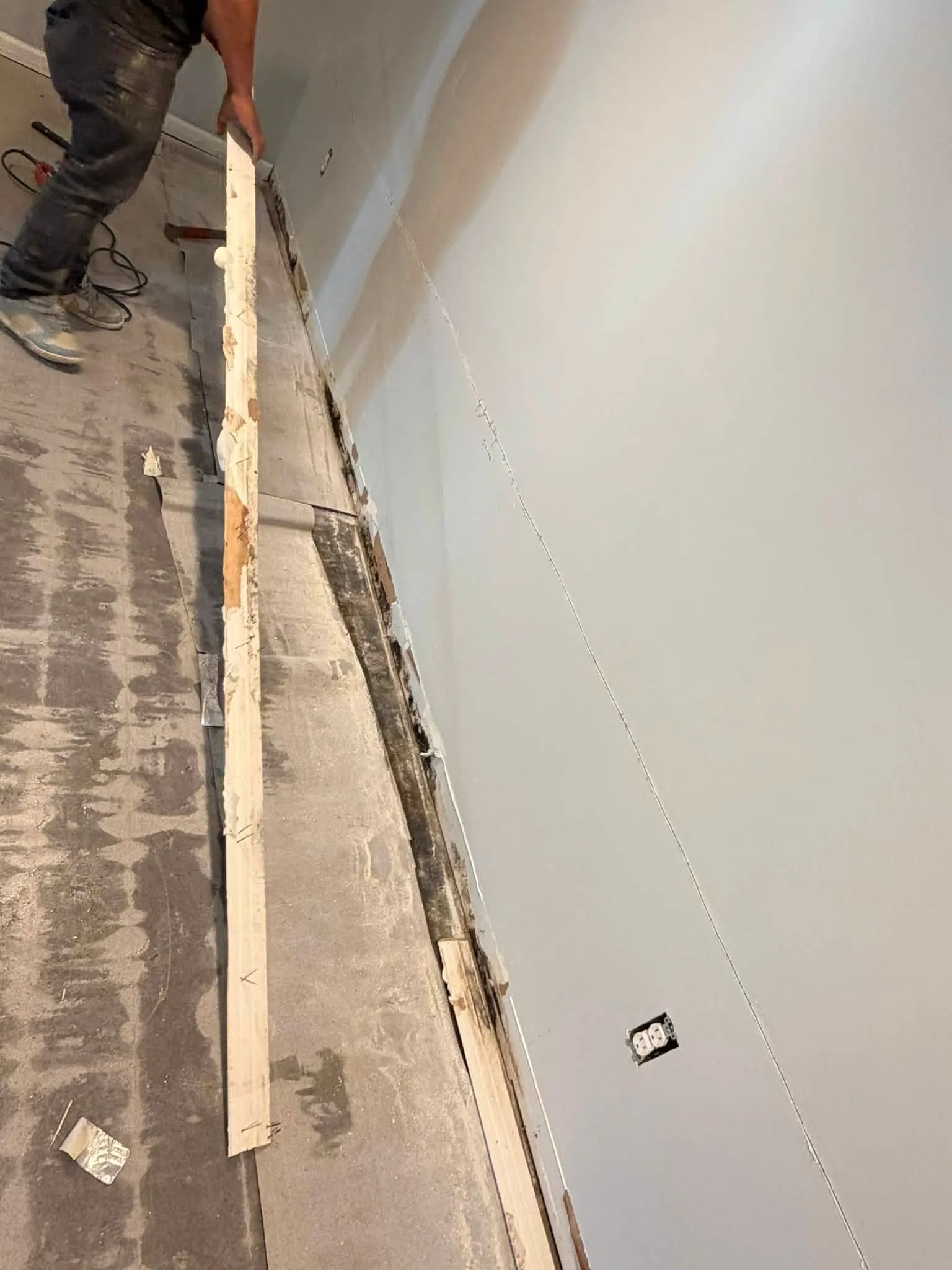 Worker removing the bottom plate along a basement wall during a Toronto waterproofing job
