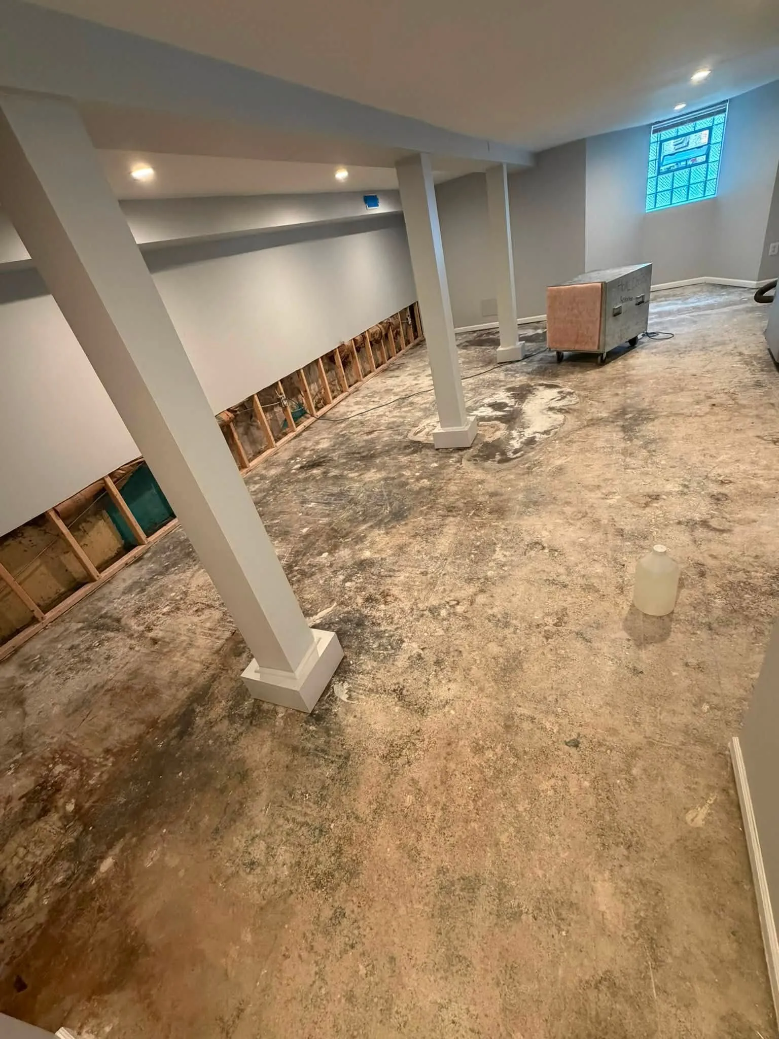 Toronto basement with water-stained concrete slab and flood-cut drywall before repair